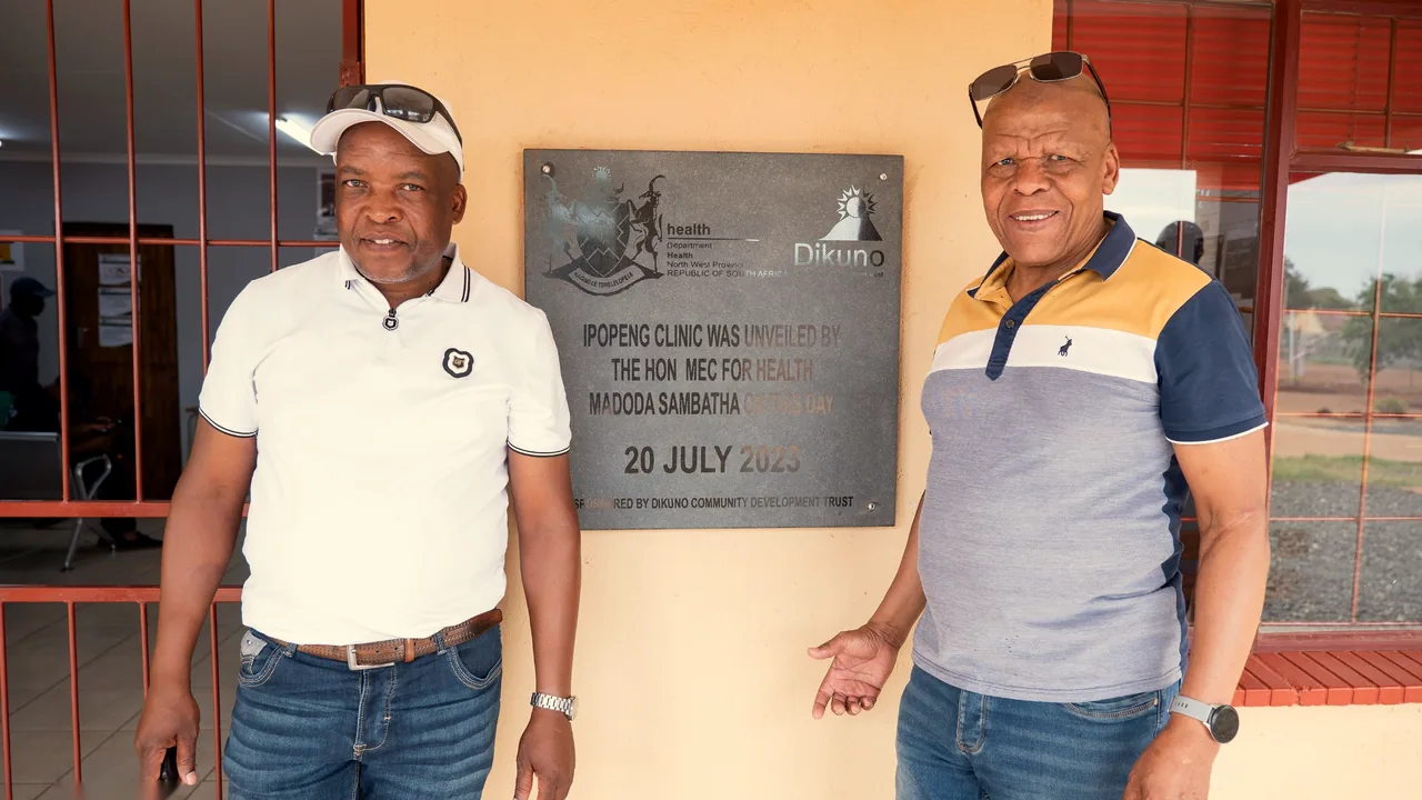 Two men beside the plaque marking the clinic's opening on 20 July 2023