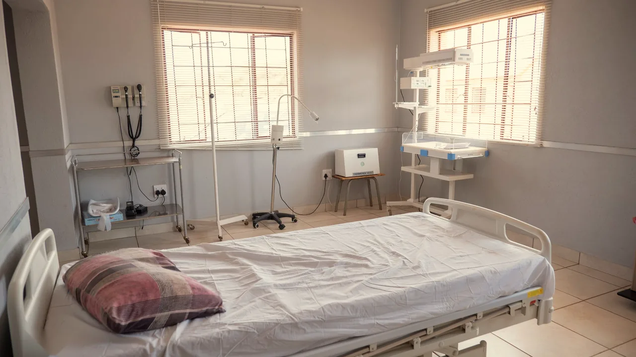 A maternity room with a bed, baby warmer and window