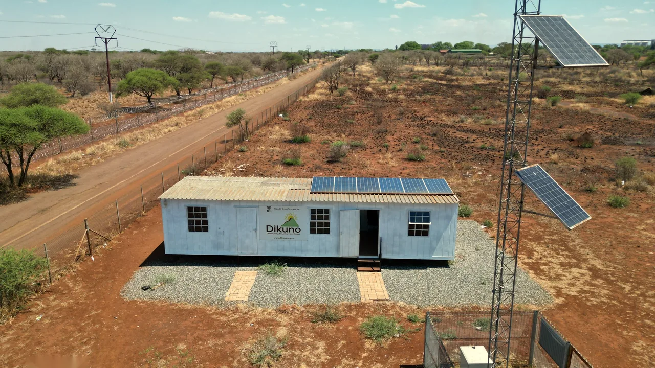 A solar-powered Wi-Fi hub building beside a communications tower on the road to the mine